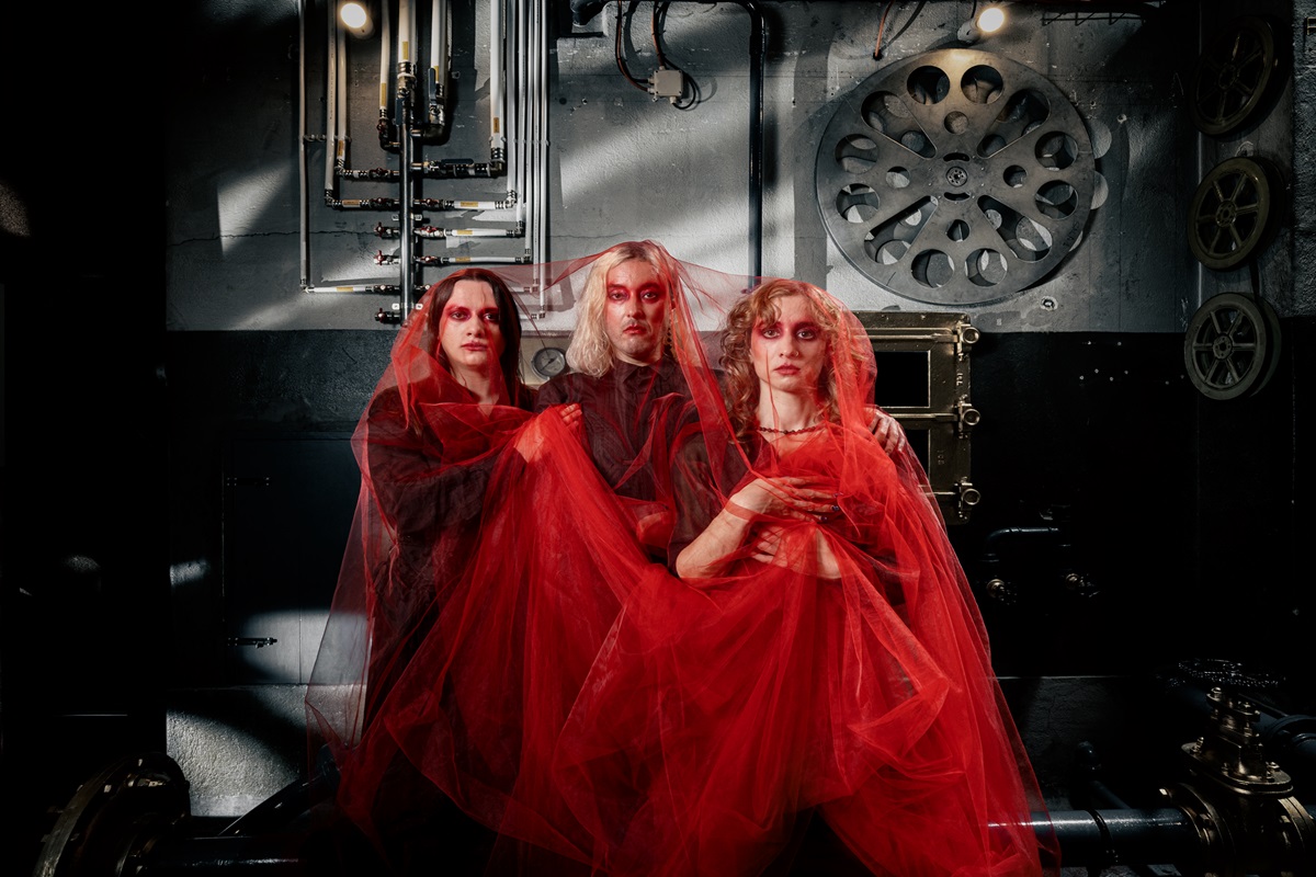 Três atores vestidos de vermelho