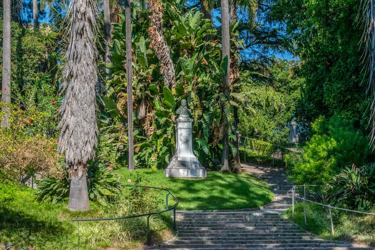 jardim com árvores de grande porte e escultura