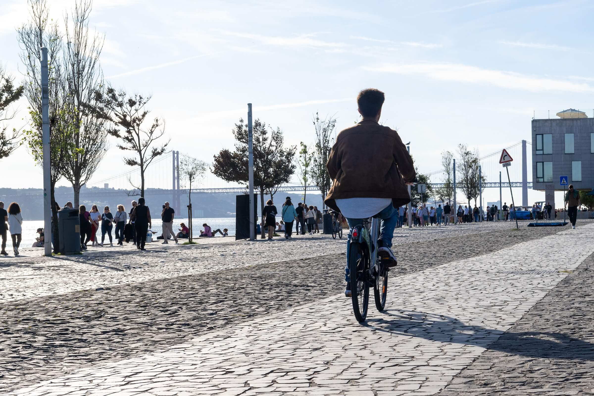 Pessoa anda de bicicleta à beira-rio na Ribeira das Naus em Lisboa